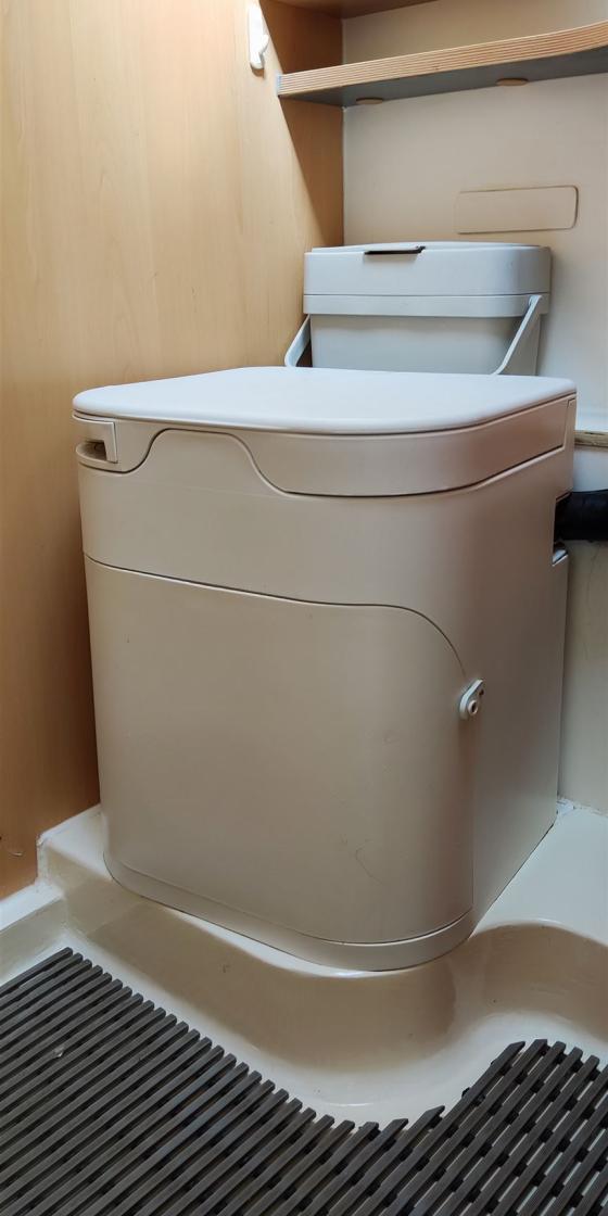 Modernes weißes WC in einem Badezimmer mit Holzregal darüber.